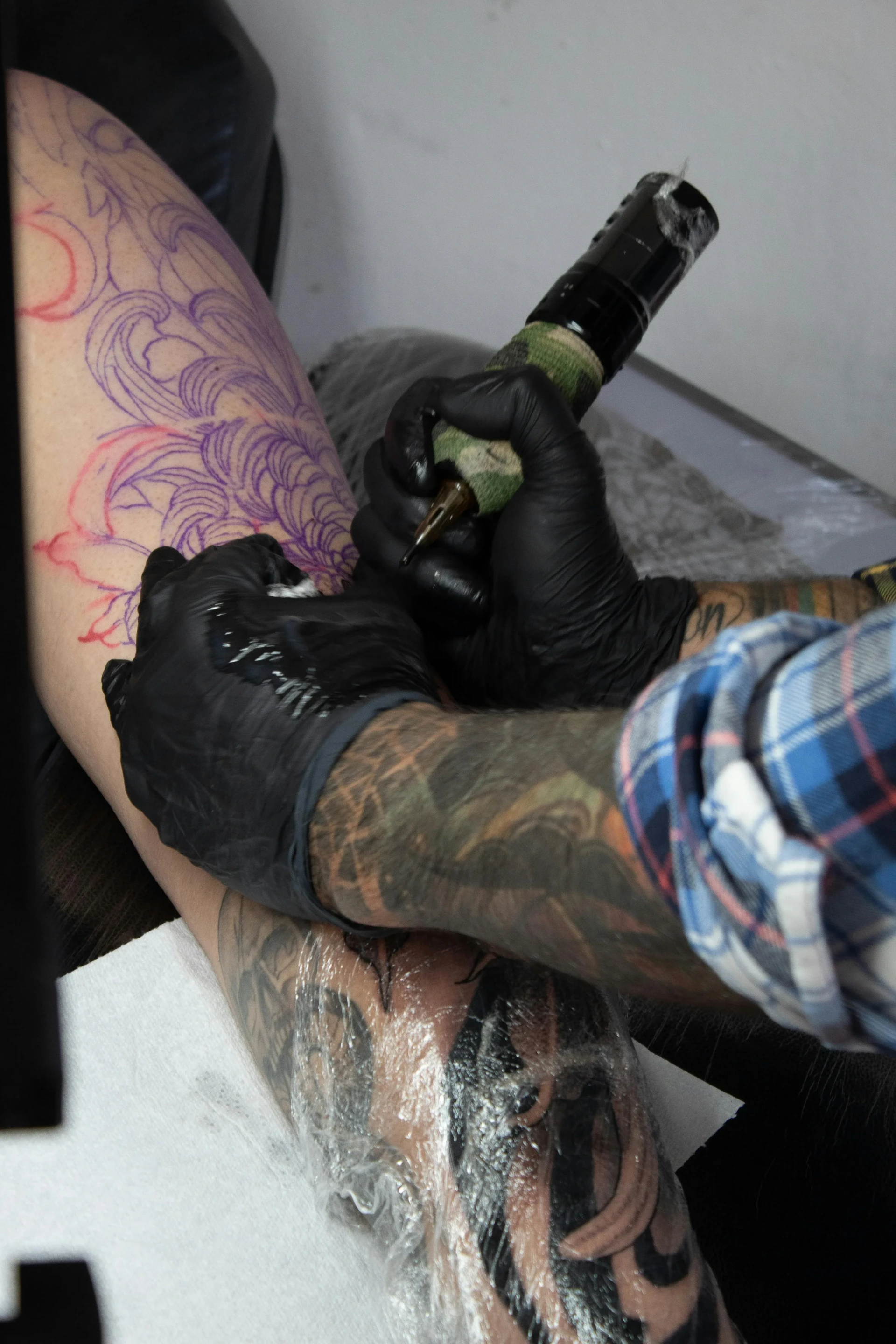 Tatoueur réalisant un tatouage sur un bras pendant une séance